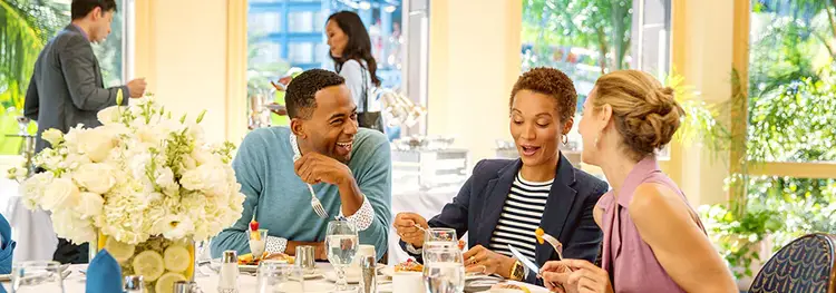 Attendees dining in an elegant room while enjoying conversation with each other