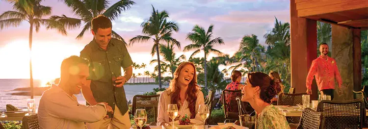 Guests enjoy a patio meal and the sunset at Aulani Resort