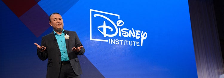 A Cast Member standing on stage giving a presentation during Disney Institute