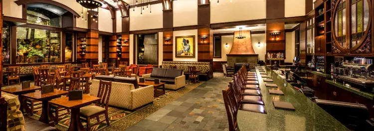 The lodge style interior of Hearthstone Lounge with dining tables, sofa seating, and a bar