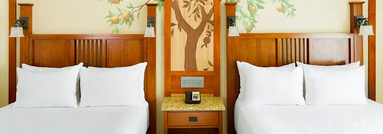 A room with 2 beds, a nightstand and a phone