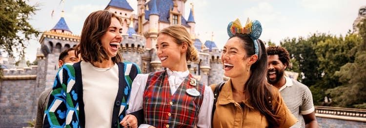 Four Guests and a Cast Member smiling and standing in front of Sleeping Beauty Castle