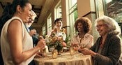 Guests enjoying beverages and small plates while standing around a cocktail table