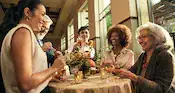 Guests enjoying beverages and small plates while standing around a cocktail table