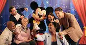 A group of Guests taking a selfie with Mickey Mouse
