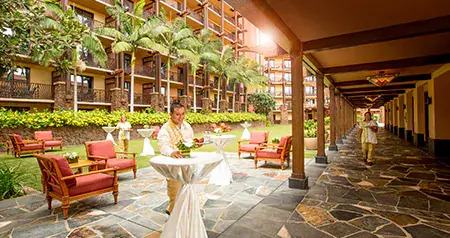 Cast Members preparing a courtyard for an event with chairs and cocktail tables at Aulani, A Disney Resort & Spa