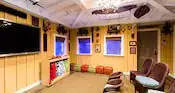 A viewing room with chairs and a large TV in Aunty’s Beach House at Aulani, A Disney Resort & Spa