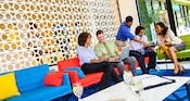 Five Guests gathered on sofas reviewing laptops and notebooks