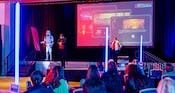 Cast Members and a stormtrooper onstage in a ballroom, presenting the Star Wars Galactic Challenge to tables full of Guests