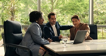 A trio of businesspeople collaborating in a Disney Meetings & Events boardroom