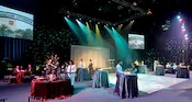 A ballroom set up for an event with people at tables in front of a stage