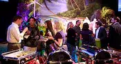 A group of guests in a ballroom standing around tables and a buffet with a touch of disney in the background
