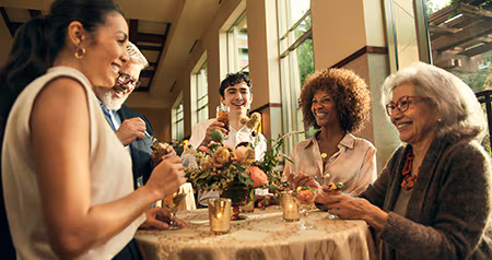 A group of smiling Guests around a table with a floral centerpiece enjoying drinks