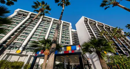 The entrance to the Pixar Place Hotel with tall palm trees in front