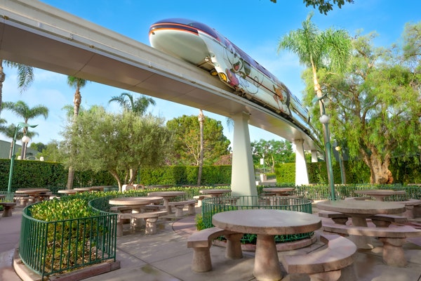 The Disneyland Monorail, passing above a scenic picnic area with many tables at the Disneyland Resort in California