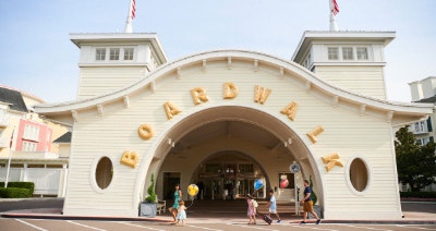 A family walking near an arched entrance with large letters that read Boardwalk