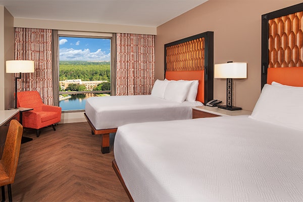 A Guest room with 2 queen beds, a chair, workspace and scenic views through a large window