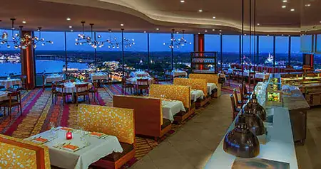 Interior of California Grill featuring a booth, table, bar seating and floor to ceiling windows overlooking Walt Disney World Resort