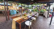 A long wooden dining table with a runner, candles and floral displays set up in the Harambe Market