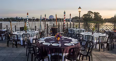 Tables with plates and flowers on Italy Isola at Epcot with Spaceship Earth in the distance