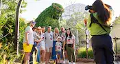 A family wearing matching Mickey Mouse themed T shirts and posing for a photo near a Te Fiti themed topiary statue