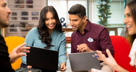 Two seated Guests looking at a laptop screen while another 2 talk with each other