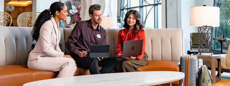 A woman, man, and woman meeting around a table on a couch in a disney meeting space