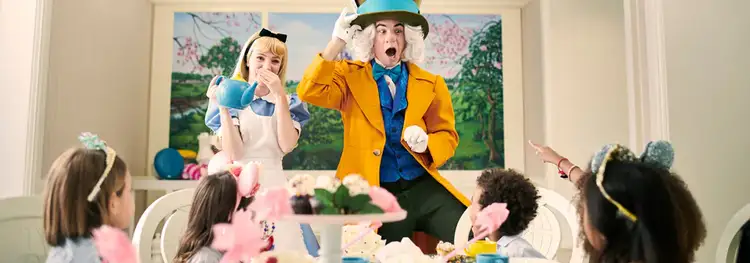 Alice and the Mad Hatter interact with 4 children, who sit at a table set with teacups and cupcakes