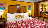 A room featuring tropical decor, a bed, wood end tables, lamps and more