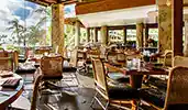 An open air restaurant featuring set tables, chairs and an ocean view
