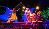 Two female dancers and 3 male fire twirlers perform in a show on a small outdoor stage