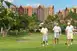 Three men in golf attire walk down a fairway each holding a golf club