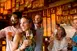 Five Guests each hold a drink at a bar
