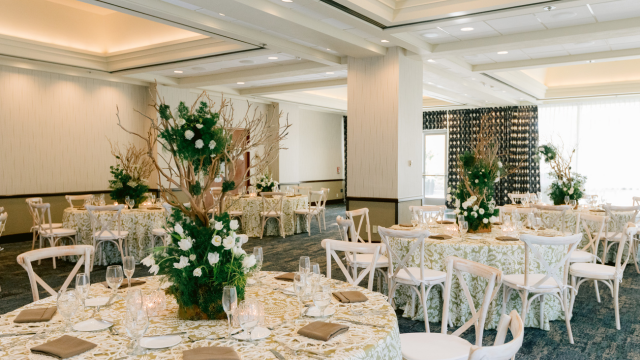 A banquet room set with round tables, chairs and tall floral centerpieces at Disneyland Hotel