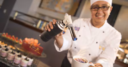 A chef caramelizing creme brulee with a culinary torch